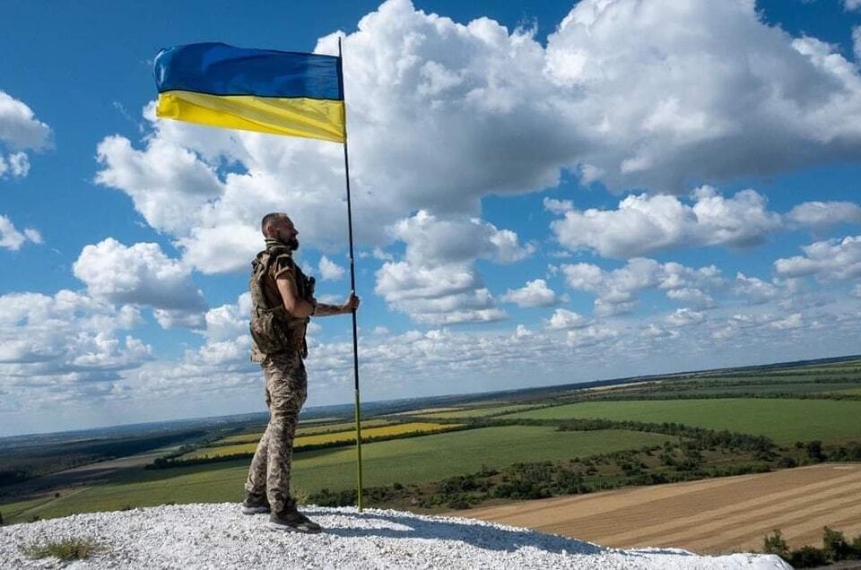 Ukrainian soldier near a Ukrainian flag