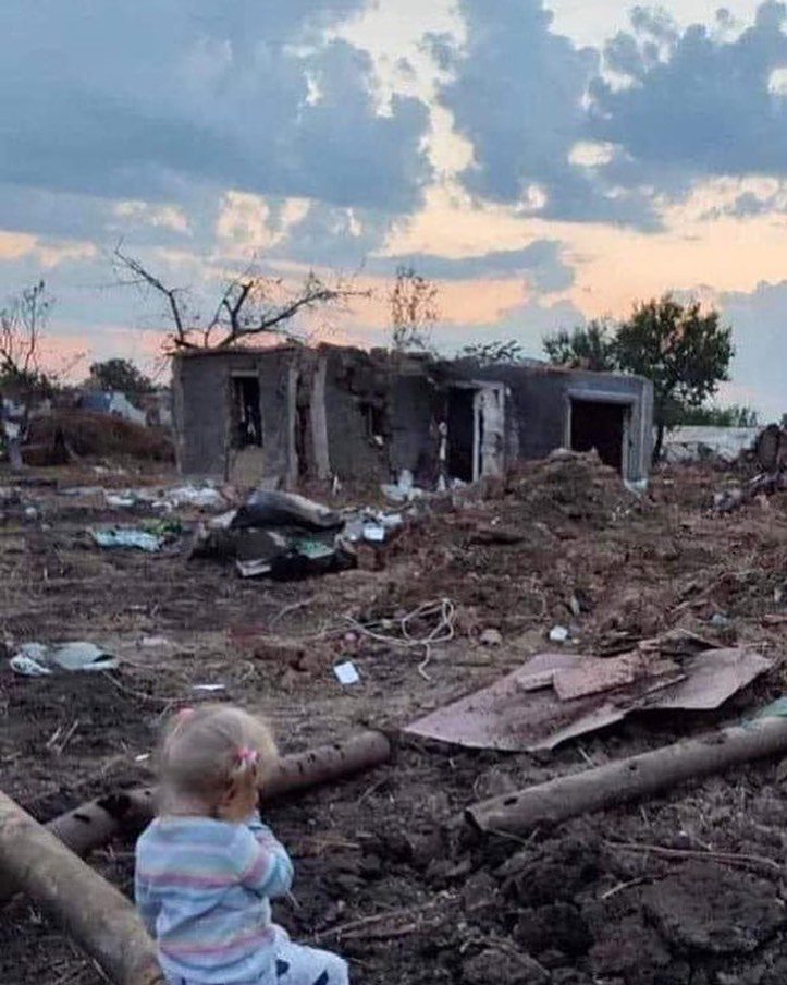 A 2 year old surveys the ruins of her house.