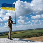 Ukrainian soldier near a Ukrainian flag